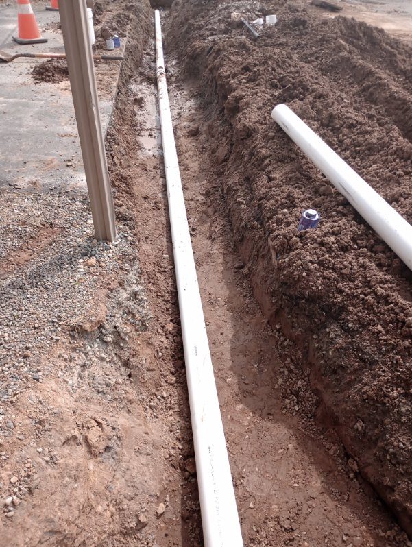 White PVC pipes laid in excavated trench during underground utility installation