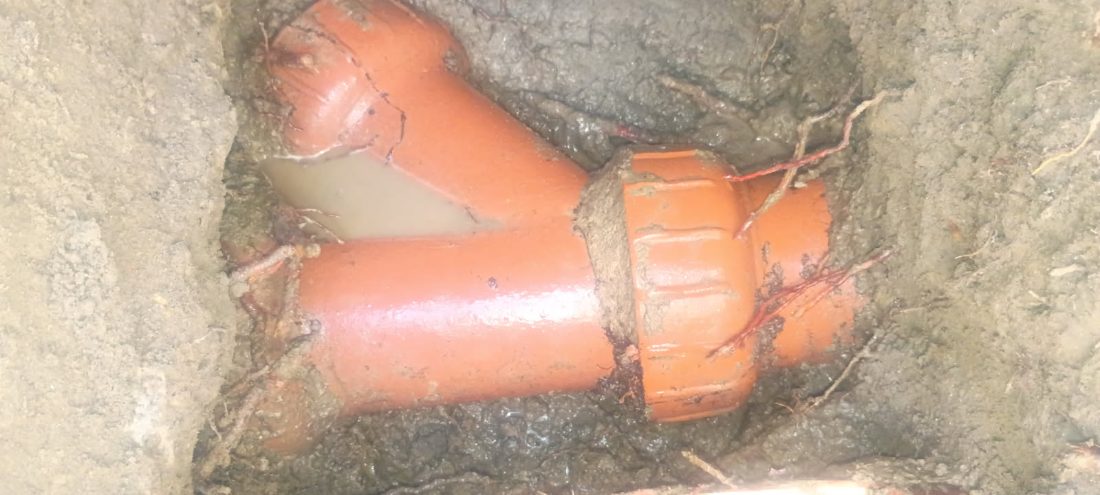 Orange PVC pipes and connectors installed in underground trench with soil