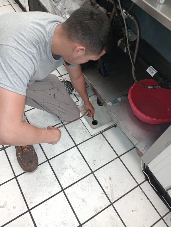Technician installing plumbing fixture under kitchen sink