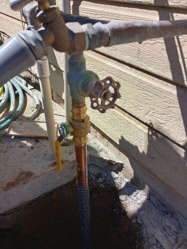 Outdoor plumbing fixture with brass valve and copper piping on concrete deck