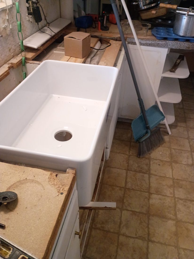 White utility sink with drain hole in basement workshop setting