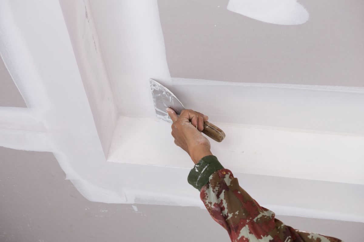 Worker applying joint compound to drywall with a putty knife