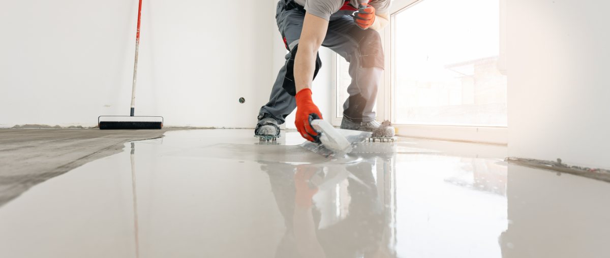 Worker in red gloves applying self-leveling epoxy coating to concrete floor