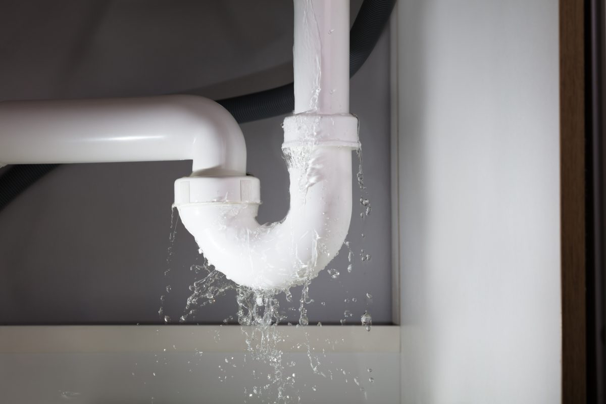 Leaking white PVC pipe with water dripping from connection joint
