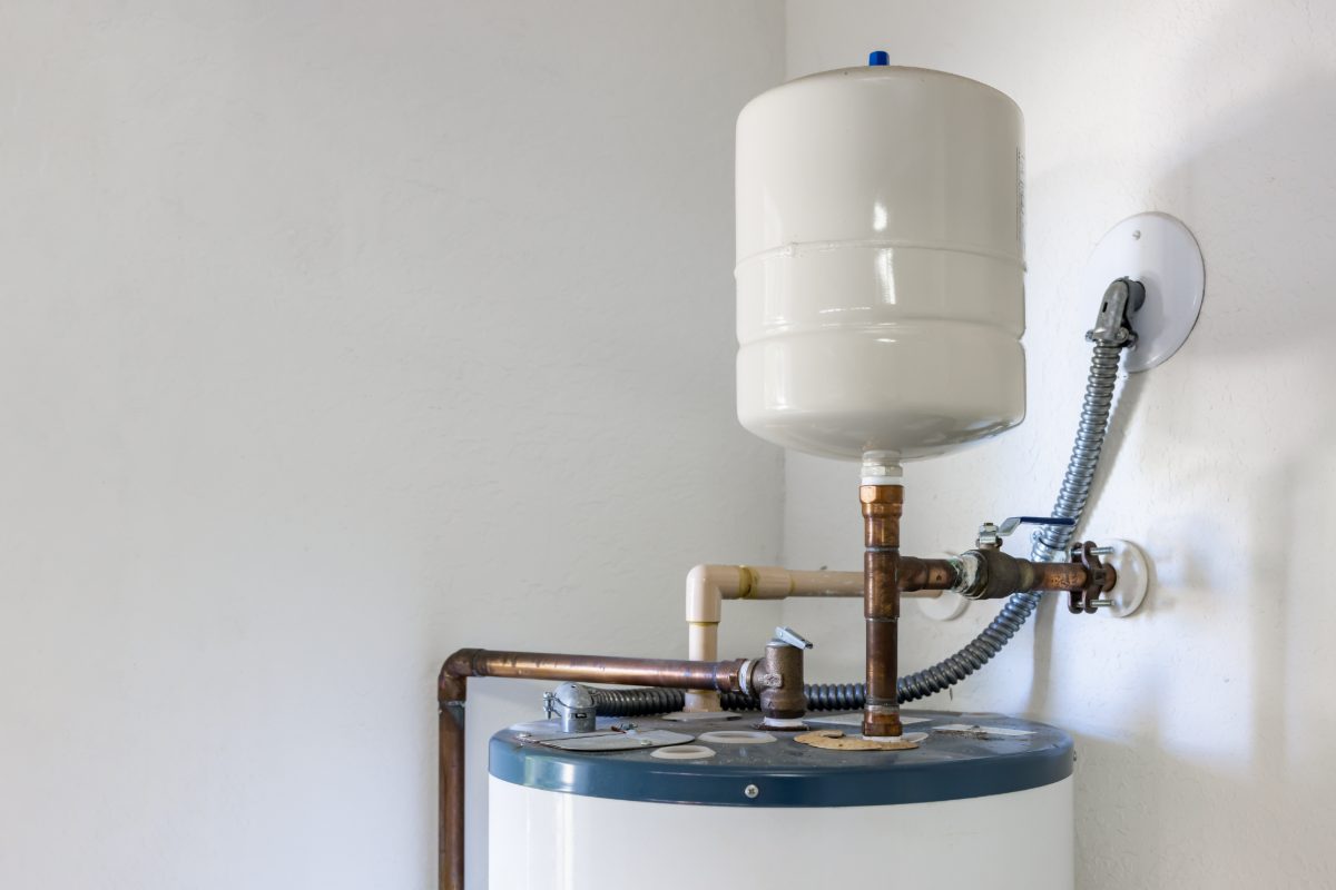 Residential water heater with expansion tank and copper piping system mounted on white wall